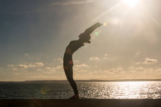 istock silhoutte of a woman practicing yoga standing backbend 2181366578