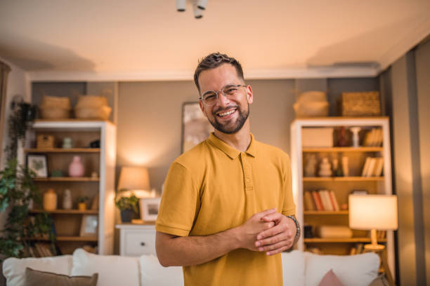 istock Carefree man looking directly at camera while standing in living room 2181368223