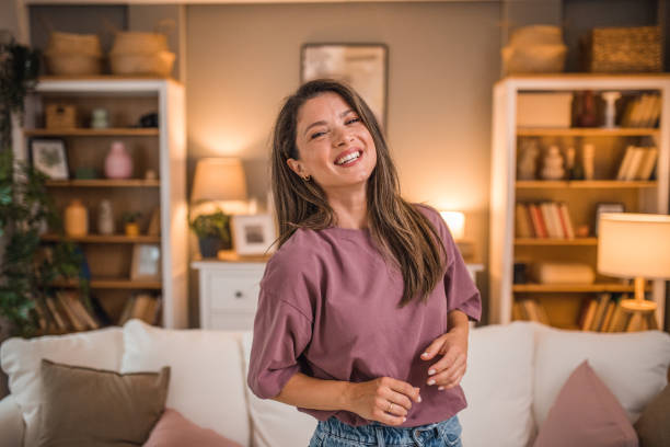 istock Gorgeous woman looking directly at camera while standing in living room 2181369140