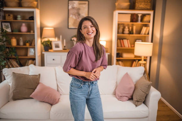istock Smiling woman looking directly at camera while standing in living room 2181369438