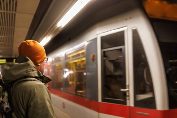 Close-up shot of mature man with backpack waiting for train on railway station