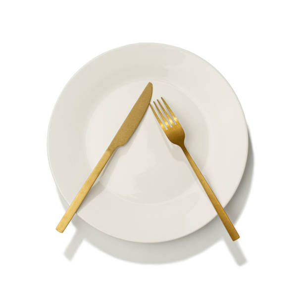 istock White plate with golden fork and knife on white isolated background 2181377891