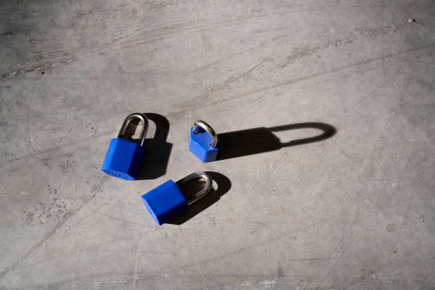 From above of similar blue metal padlocks scattered on gray concrete floor with scratches in daylight
