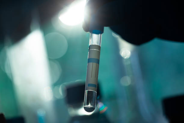 A scientist's hand holds a test tube with a substance on dark