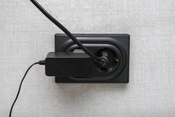 A sleek black charger is currently plugged into a wall socket, enabling it to provide power to various electronic devices