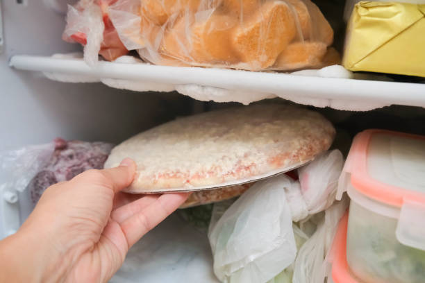 istock A hand taking frozen pizza from a freezer 2181384438