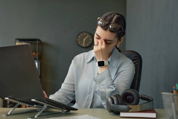 istock Exhausted Girl Rubbing Forehead Sitting at Office Desk 2181384645