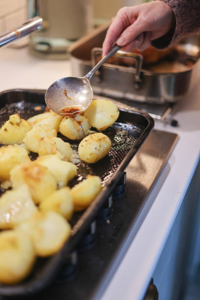 istock Basting part cooked roast potatoes in meat juices in a hot roasting pan 2181384798