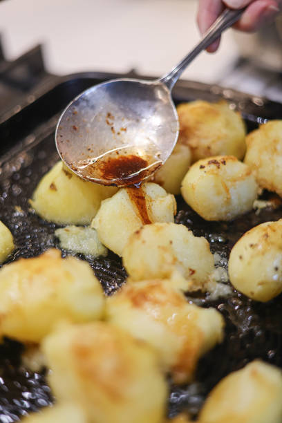 istock Basting part cooked roast potatoes in meat juices in a hot roasting pan 2181384833