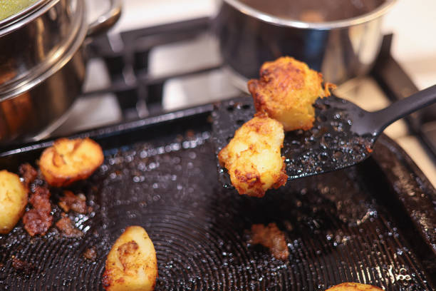 Lifting hot crispy roast potatoes off the baking tray ready to be plated up