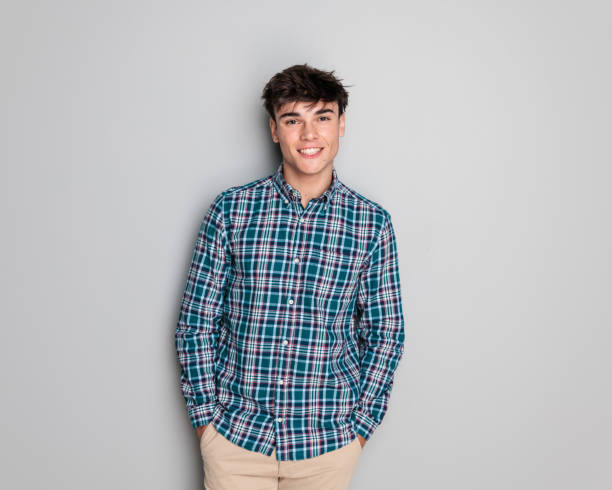 istock sexy young man in checkered shirt smiling while holding hands in pockets 2181386958