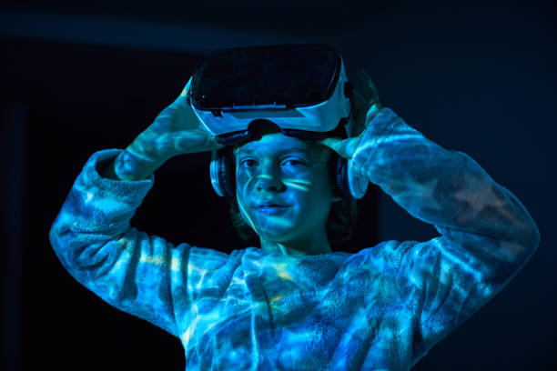 istock Little boy adjusting VR headset and looking at camera in darknes 2181392325