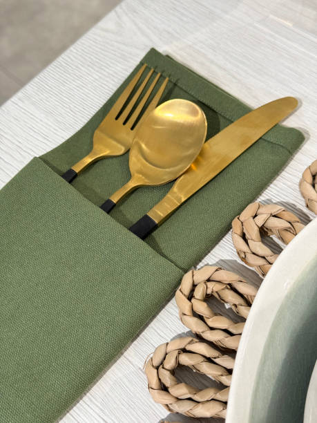 istock Image of elegantly set dinner party table / gold cutlery, knife, fork, spoon, green napkin / dining table decor 2181396426