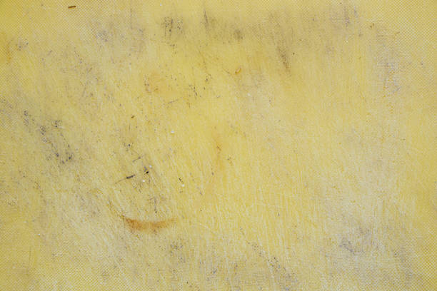 Plastic yellow cutting board all in cuts from a knife, the board is scratched