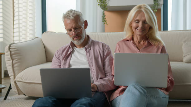 istock Happy successful elderly Caucasian couple senior man woman using laptop computer remote work male female shopping banking Internet online e-commerce wife husband smile sofa family together addict home 2181399293