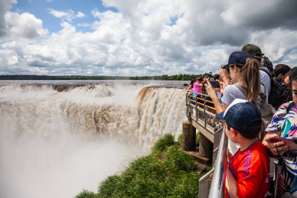 Visitors at the observation point for the Devil's Throat waterfall at Iguazu Falls, Argentina. Visitors crowding the observation point at the Devil's Throat, or Devil's Gorge, in Argentina. Garganta del Diablo is a U-shaped waterfall about 150m.in length and 82m high. and is one of many cascades of the falls. devils throat stock pictures, royalty-free photos & images