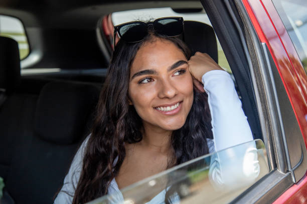 istock smiling young woman inside car looking out the window 2181407912