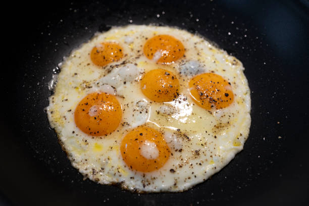 Fried Eggs in pan with black pepper and salt