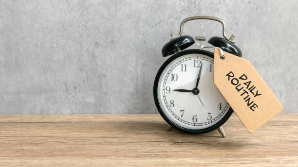 istock Alarm clock tie with tag written with ' Daily Routine' on wooden table with copy space. 2181417447
