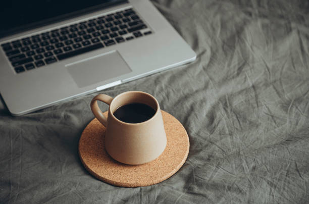 istock Espresso coffee in brown ceramic cup on grey bed with laptop. 2181431868