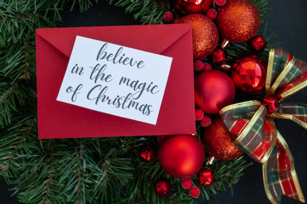 istock Christmas handmade wreath made of festive decorations with red envelope and paper note with BELIEVE IN THE MAGIC OF CHRISTMAS text. Winter holiday celebration greeting card 2181436603