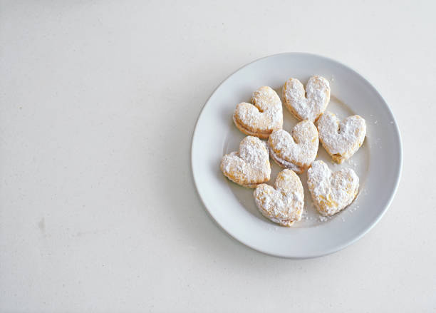 Heart-shaped alfajores with powdered sugar on a white plate