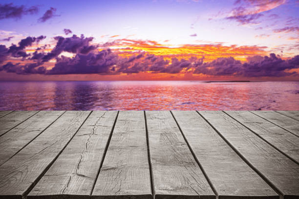 Empty wooden table top with tropical ocean sunset and dramatic sky background