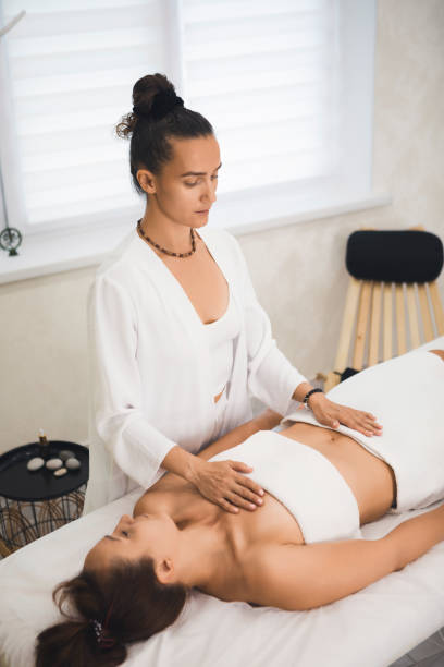 istock Lymphatic drainage massage. Female therapist works client lying on back in pro salon, vertical format, selective focus. 2181446148