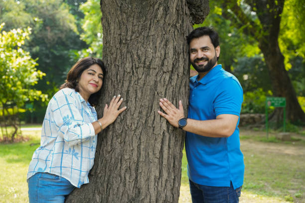 istock young happy indian couple at park hugs large tree, Save environment, ecology, climate change, Fresh oxygen. Deforestation. 2181448623