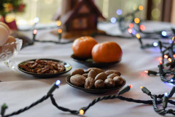Background of a rustic, festive table with nuts, tangerines, lights and Christmas decorations as cozy lights that create a festive atmosphere for the December holidays