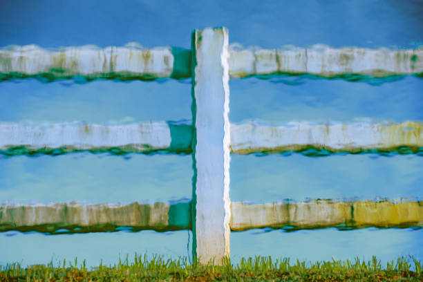 Abstract Series : Reflection of white concrete fence in water. Shadow of white concrete fence in water. White fence reflected in the water near the stream.