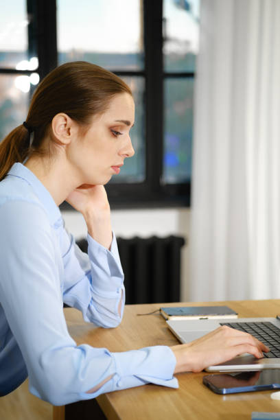 istock Professional woman typing on a laptop while sitting at a desk in a bright office environment 2181455038