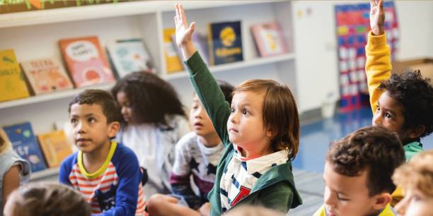 istock Children in a classroom raising hands. 2181455841