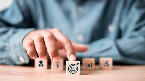 istock Hand touching and push target board which printing on wooden cube block. Goal and target, success and business target concept, project management, company strategy. 2181456239