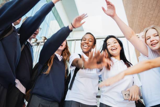 istock Group of diverse students in uniforms, smiling and raising hands. 2181458502
