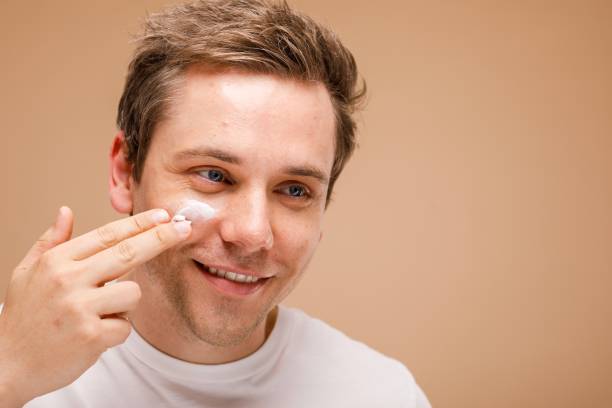 istock Man applying face cream, smiling. Skincare routine for men. 2181462741