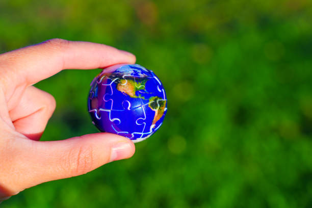 istock Hand Holding Puzzle Earth Globe Against Green Background 2181467212