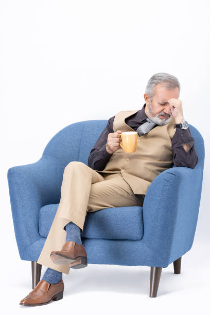 istock Senior man drinking coffee sitting on sofa on white background stock photo 2181468190