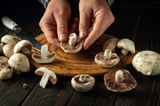 istock Chef sorts champignons mushrooms on the kitchen table before cooking. Concept of preparing mushrooms for a delicious dinner or breakfast 2181472882