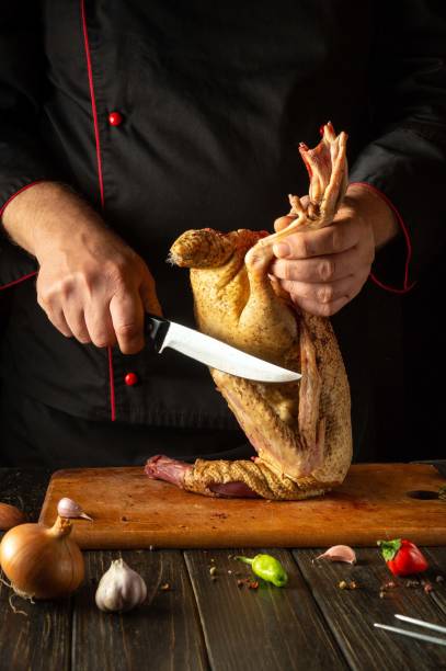 istock In a warm kitchen, a chef expertly holds a duck while cutting it with a sharp knife, surrounded by fresh vegetables and spices, showcasing culinary skills and preparation techniques 2181472897
