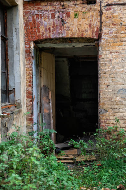 istock Abandoned broken door leads into a decayed building with brick walls 2181475597