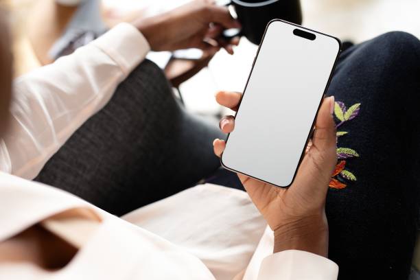 Person holding a smartphone with a blank screen, sitting comfortably.