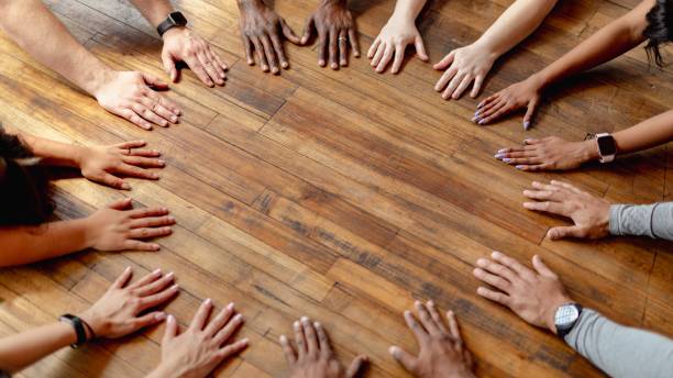 Diverse hands form a circle on a wooden floor. Unity, teamwork, and diversity. Hands circle team unity. Diverse people hands together partnership on wooden floor. Diverse ethnics hands circle together