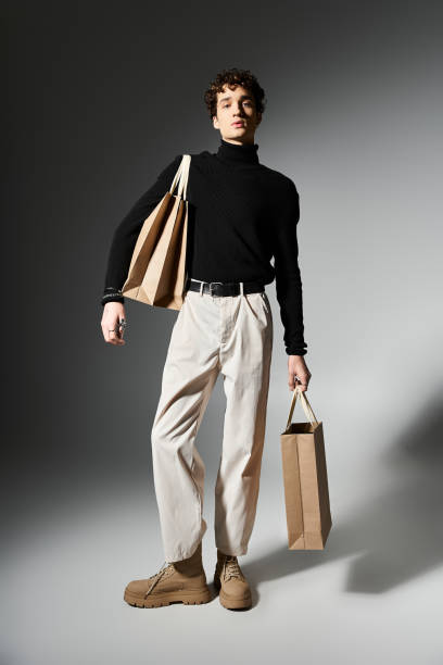 istock Stylish young man showcasing shopping bags in a festive studio setting during Black Friday 2181480929