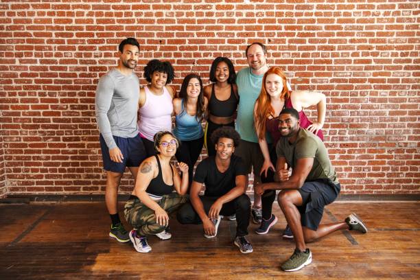 istock Group of diverse people posing in casual workout attire against brick wall. 2181480982