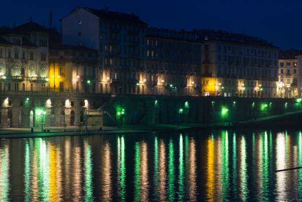 It is almost night in Turin. along the Po River. The multicolored lights of the city are reflected on the still waters.