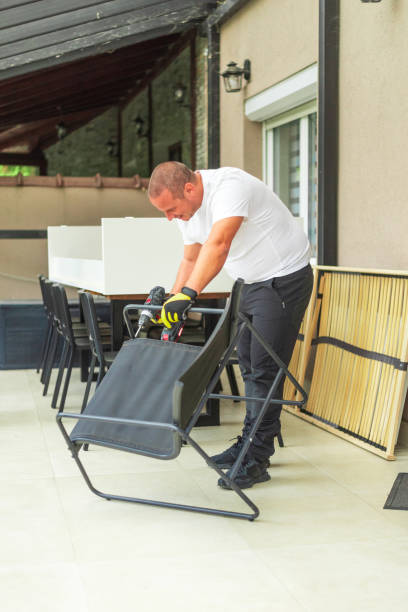 istock Handyman assembling black metal chair using cordless drill on terrace 2181482997