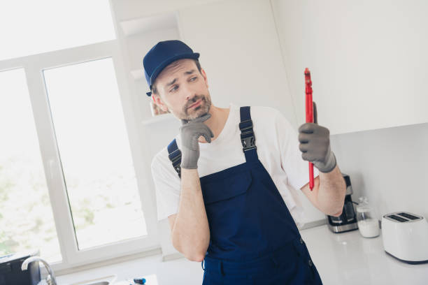 istock Thoughtful young handyman in blue overalls contemplating a plumbing task in a modern kitchen environment 2181487983