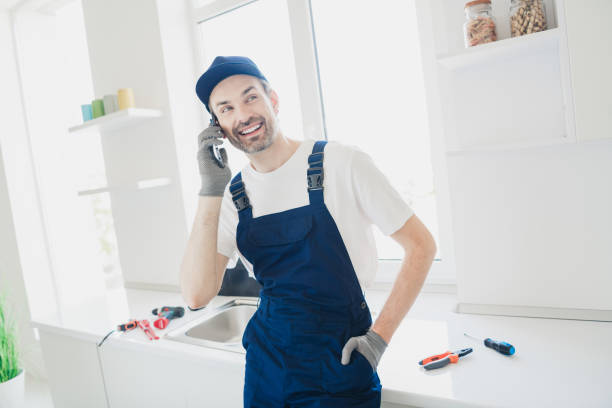 Friendly handyman in blue overalls takes a phone call while working in a bright modern kitchen environment