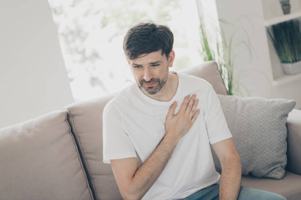 istock Man experiencing chest discomfort while sitting on a comfortable sofa in a cozy living room, reflecting health concerns and anxiety 2181488780